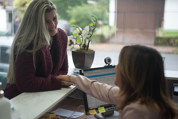 Cássia recepcionando uma cliente na Clínica Wüst em Rolante-RS, oferecendo atendimento acolhedor e personalizado desde a entrada.