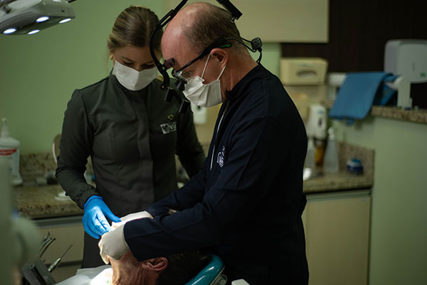 Dr. Pablo e Dra. Luana em atendimento conjunto a uma paciente na Clínica Wüst em Rolante-RS, oferecendo cuidado odontológico personalizado e especializado.