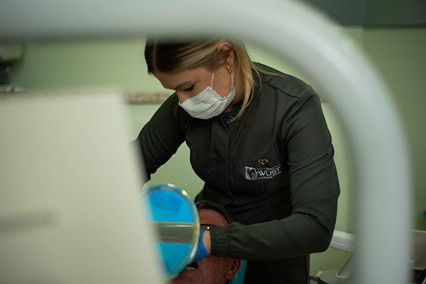 Dra. Luana atendendo um paciente na Clínica Wüst em Rolante-RS, oferecendo cuidado odontológico personalizado e atencioso.